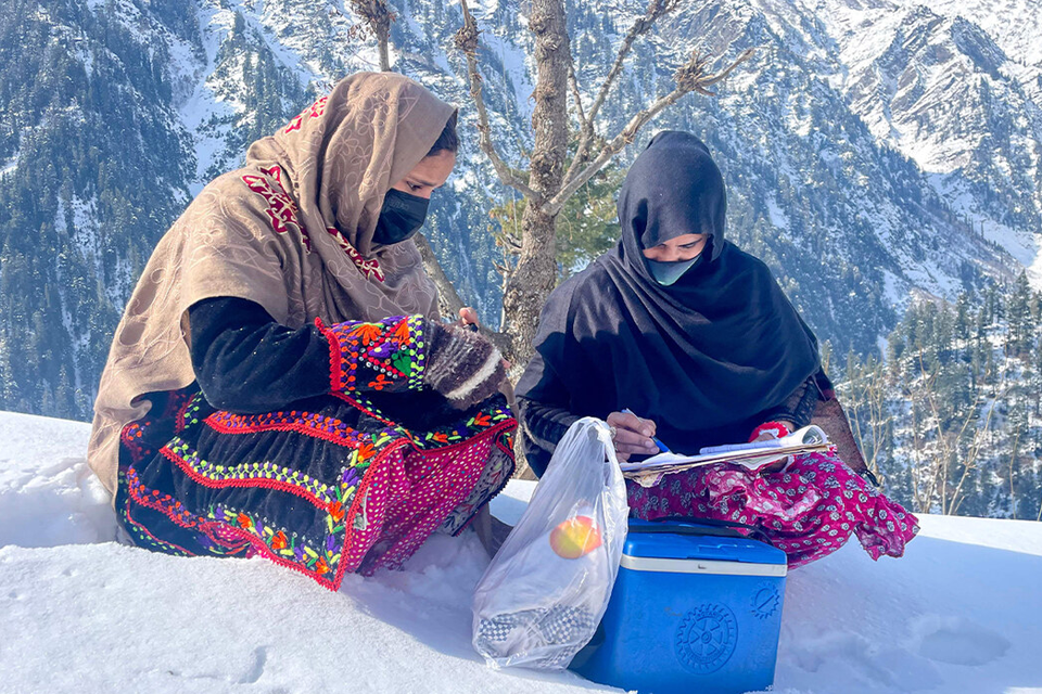 Health workers sit on snow during a polio vaccination drive in Azad Jammu Kashmir's Neelum Valley on February 4, 2025. (AFP